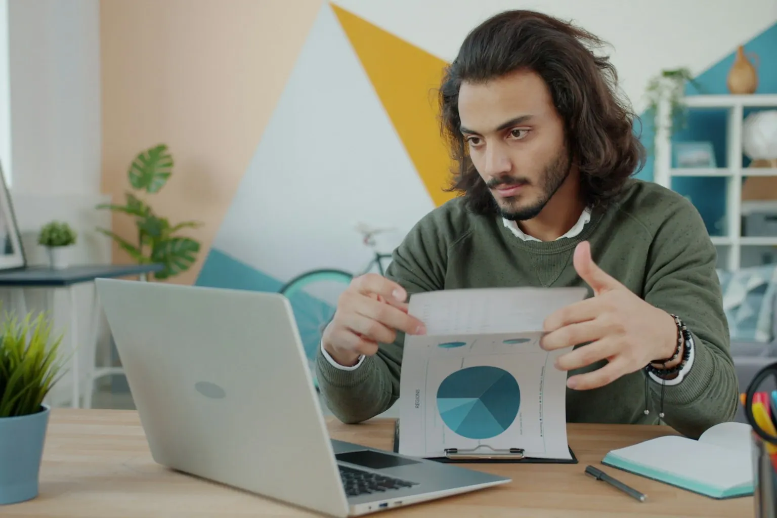 شخص يراجع أوراقًا أمام حاسوب محمول في المنزل